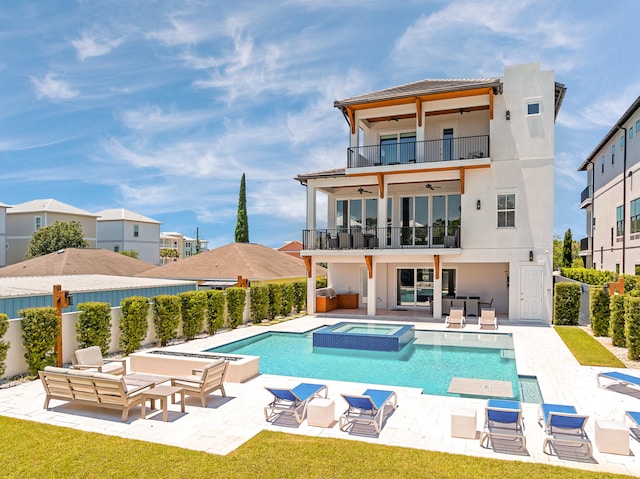 rear view of house featuring ceiling fan, an outdoor hangout area, a balcony, a patio area, and a swimming pool with hot tub