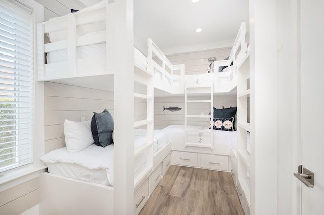 bedroom with wood walls and light hardwood / wood-style flooring