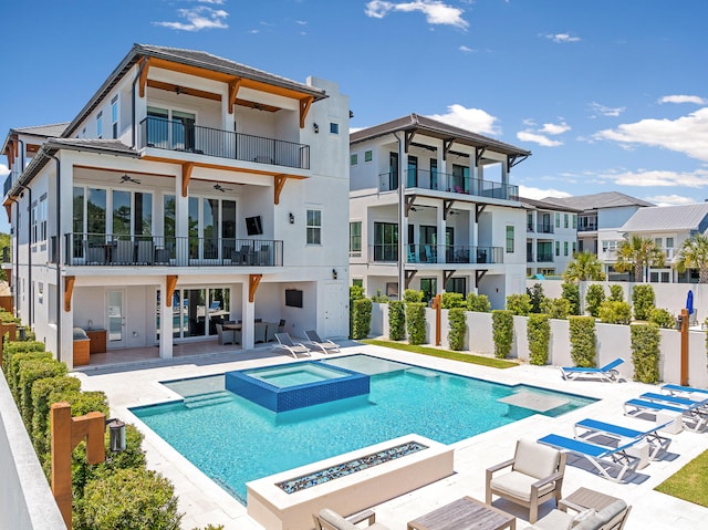 back of property featuring a swimming pool with hot tub, a patio, a fire pit, and ceiling fan