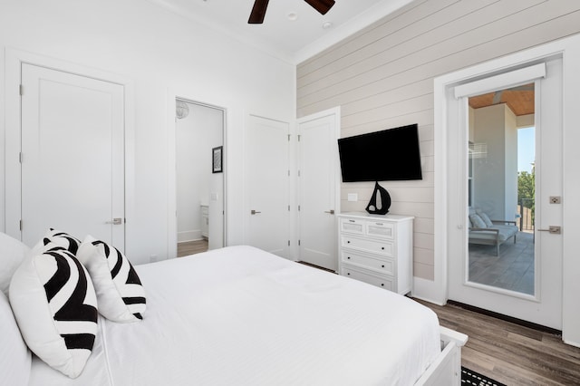 bedroom featuring ceiling fan, wood walls, light wood-type flooring, and ensuite bath