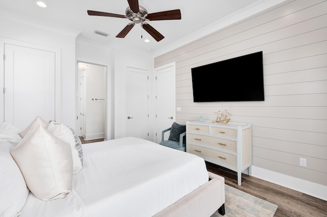 bedroom featuring ceiling fan, wood walls, light wood-type flooring, and crown molding