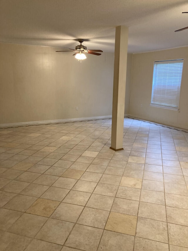 tiled empty room featuring ceiling fan and a textured ceiling