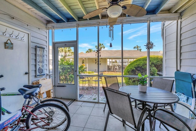 sunroom with ceiling fan and beam ceiling