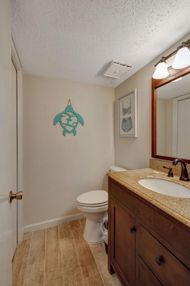 bathroom with vanity, wood-type flooring, a textured ceiling, and toilet