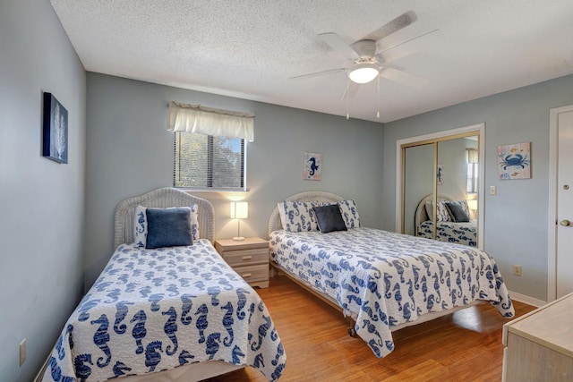 bedroom with ceiling fan, a closet, light hardwood / wood-style floors, and a textured ceiling