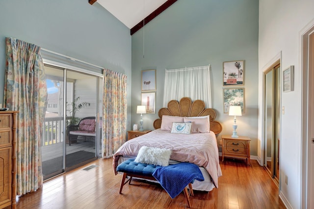 bedroom with high vaulted ceiling, wood-type flooring, and access to outside