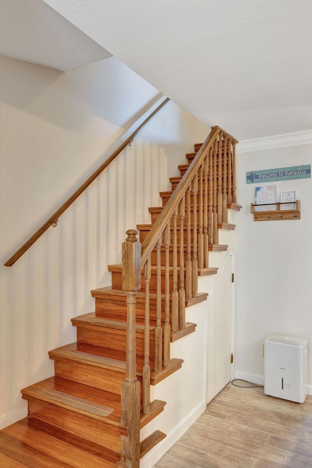 staircase with crown molding and hardwood / wood-style flooring