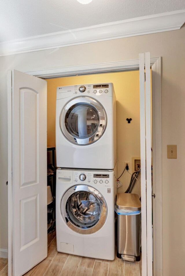 laundry area featuring crown molding and stacked washer and clothes dryer