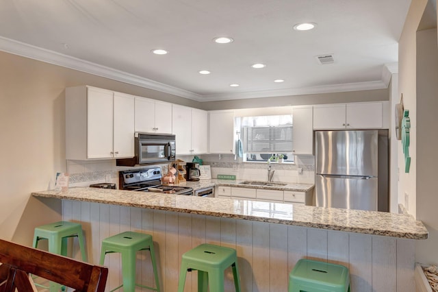 kitchen with light stone countertops, stainless steel fridge, electric range oven, sink, and white cabinetry