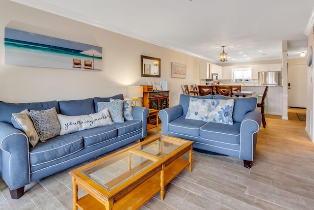 living room featuring a chandelier, light hardwood / wood-style floors, and crown molding