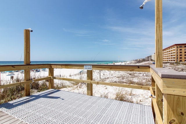 wooden deck with a water view and a view of the beach