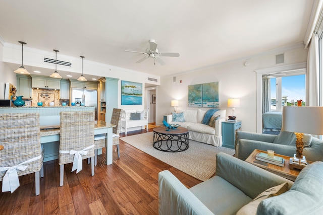 living room with dark wood-type flooring, ornamental molding, and ceiling fan