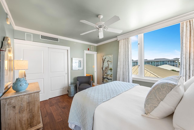 bedroom featuring ceiling fan, a closet, ornamental molding, and dark wood-type flooring