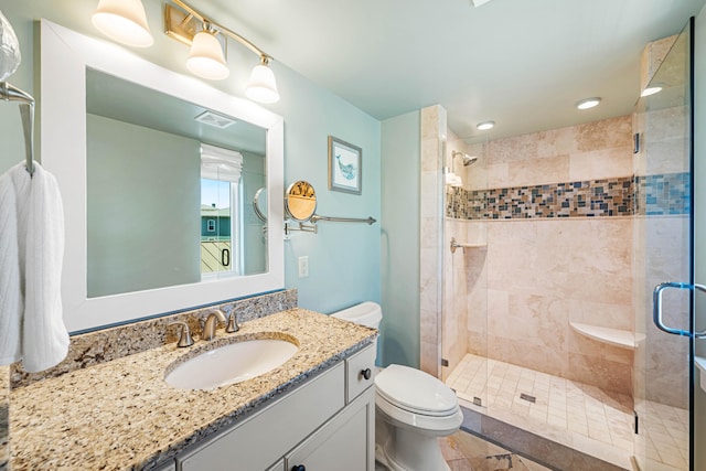 bathroom featuring a shower with door, tile flooring, toilet, and vanity