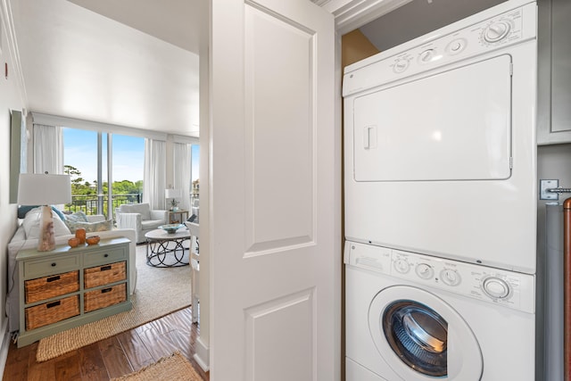 laundry area featuring stacked washer / dryer and wood-type flooring