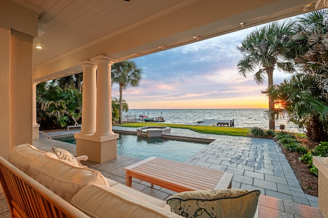 patio terrace at dusk featuring outdoor lounge area and a water view