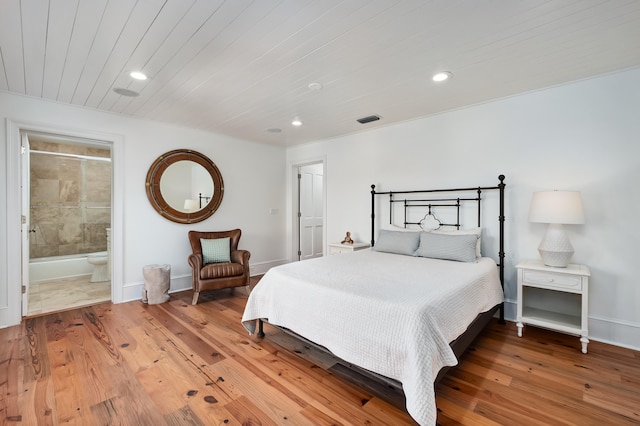 bedroom with connected bathroom and hardwood / wood-style flooring