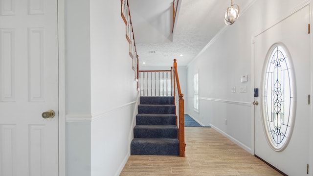 foyer with ornamental molding and light hardwood / wood-style floors