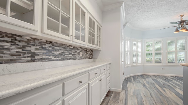 kitchen with light hardwood / wood-style flooring, ceiling fan, tasteful backsplash, white cabinets, and a textured ceiling