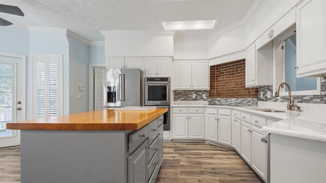 kitchen featuring butcher block counters, tasteful backsplash, white cabinetry, and appliances with stainless steel finishes