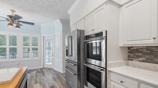 kitchen featuring crown molding, stainless steel appliances, backsplash, wood-type flooring, and ceiling fan