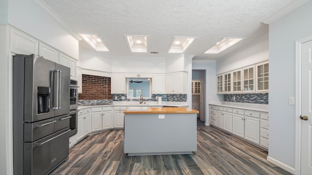 kitchen with crown molding, high quality fridge, backsplash, wood counters, and white cabinets