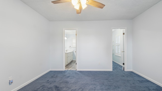 unfurnished bedroom with carpet flooring, ensuite bathroom, ceiling fan, and a textured ceiling