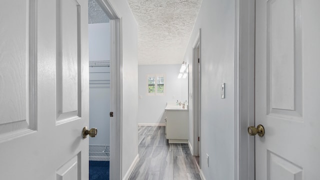 hallway with light hardwood / wood-style floors and a textured ceiling