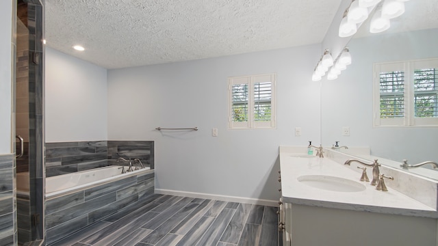 bathroom featuring shower with separate bathtub, oversized vanity, double sink, and a textured ceiling