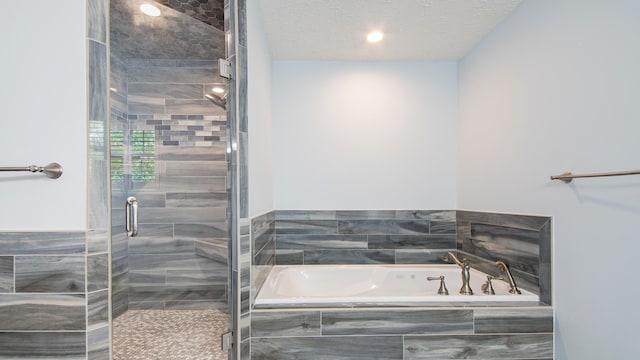 bathroom featuring separate shower and tub and a textured ceiling