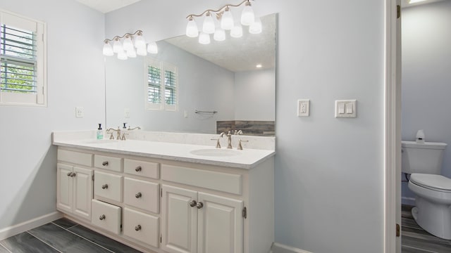 bathroom with wood-type flooring, double sink, toilet, and large vanity