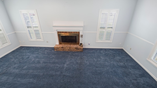 unfurnished living room with a brick fireplace and dark colored carpet