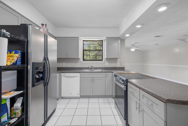 kitchen with a textured ceiling, appliances with stainless steel finishes, sink, ceiling fan, and light tile floors