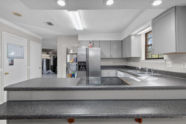 kitchen with stainless steel fridge, gray cabinetry, kitchen peninsula, black electric cooktop, and sink