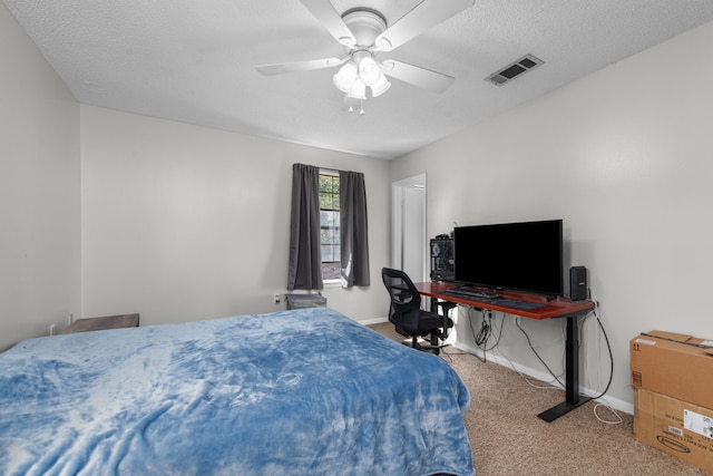 bedroom with ceiling fan, carpet floors, and a textured ceiling