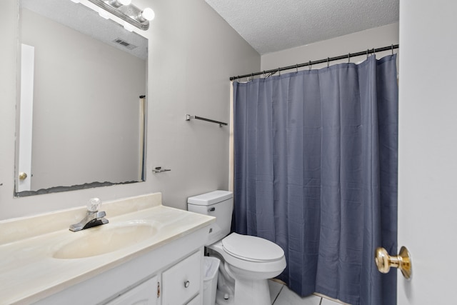 bathroom with tile floors, vanity with extensive cabinet space, a textured ceiling, and toilet