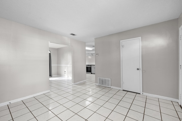 spare room featuring light tile flooring and a textured ceiling