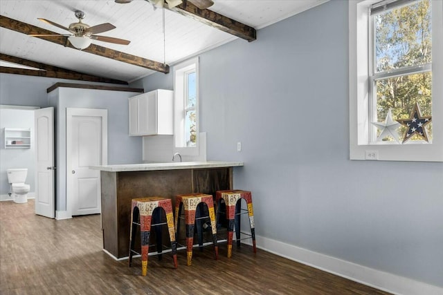 kitchen featuring wooden ceiling, vaulted ceiling with beams, dark hardwood / wood-style floors, ceiling fan, and white cabinetry