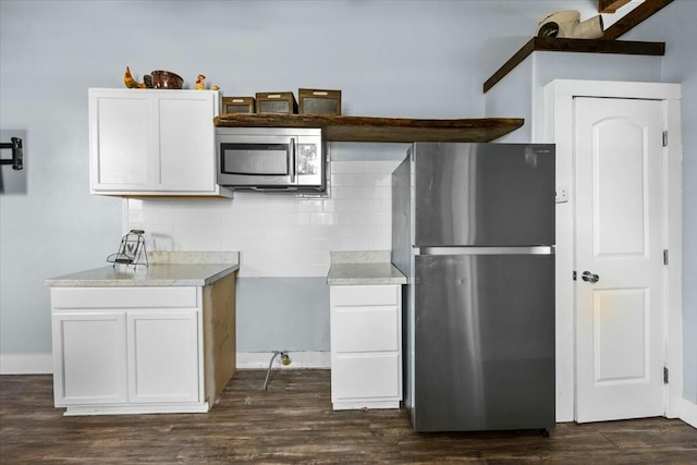 kitchen featuring white cabinets, decorative backsplash, stainless steel appliances, and dark hardwood / wood-style floors