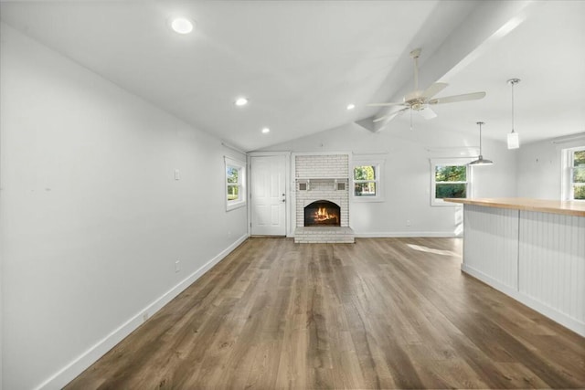 unfurnished living room with dark hardwood / wood-style floors, ceiling fan, a fireplace, and vaulted ceiling