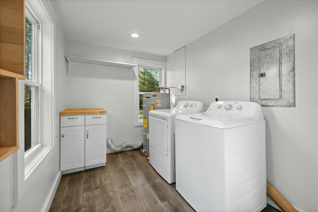 clothes washing area featuring cabinets, electric water heater, electric panel, dark hardwood / wood-style floors, and independent washer and dryer