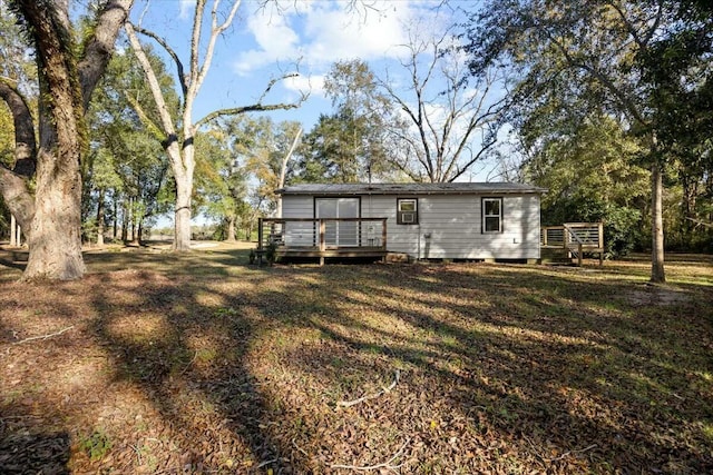 rear view of property with a lawn and a wooden deck