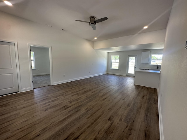 unfurnished living room featuring ceiling fan and dark wood-type flooring