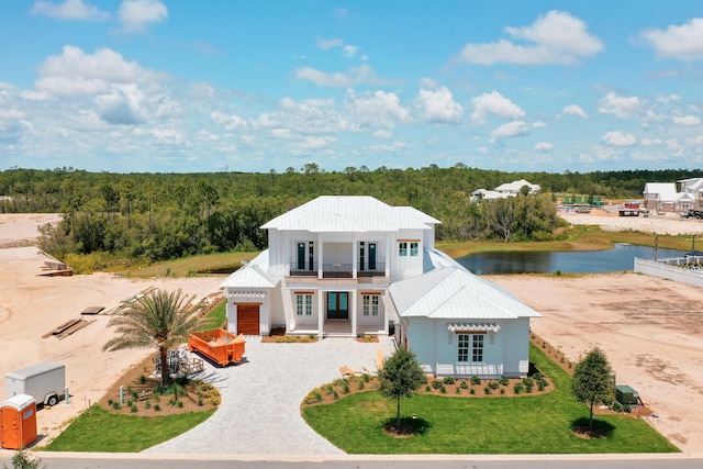 view of front of house featuring a water view, a front lawn, and a balcony