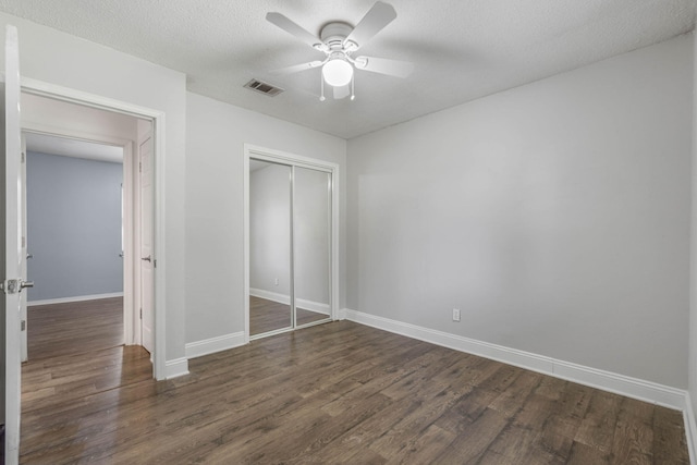 unfurnished bedroom with dark hardwood / wood-style flooring, ceiling fan, a closet, and a textured ceiling