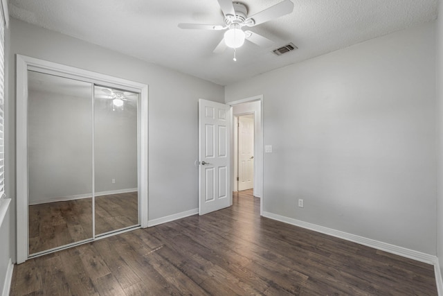 unfurnished bedroom with ceiling fan, dark hardwood / wood-style flooring, a textured ceiling, and a closet