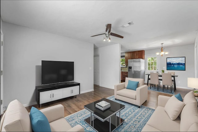 living room with hardwood / wood-style floors and ceiling fan with notable chandelier