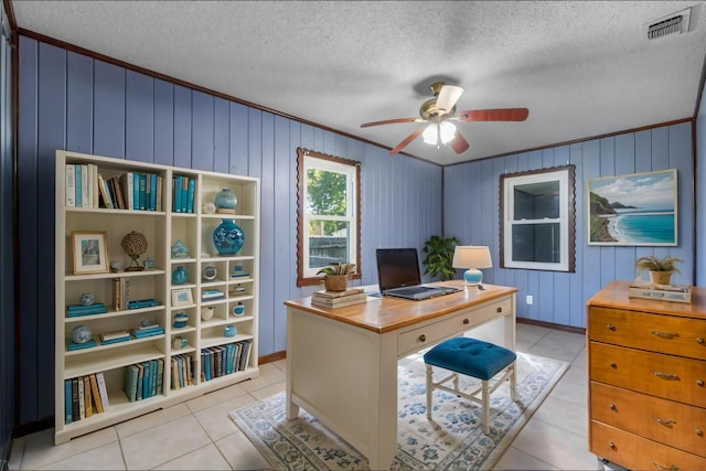 tiled home office featuring ceiling fan, wooden walls, crown molding, and a textured ceiling