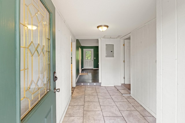 hall featuring electric panel, wooden walls, light tile patterned floors, and a textured ceiling