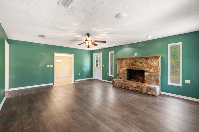 unfurnished living room with a textured ceiling, a stone fireplace, ceiling fan, and dark hardwood / wood-style floors